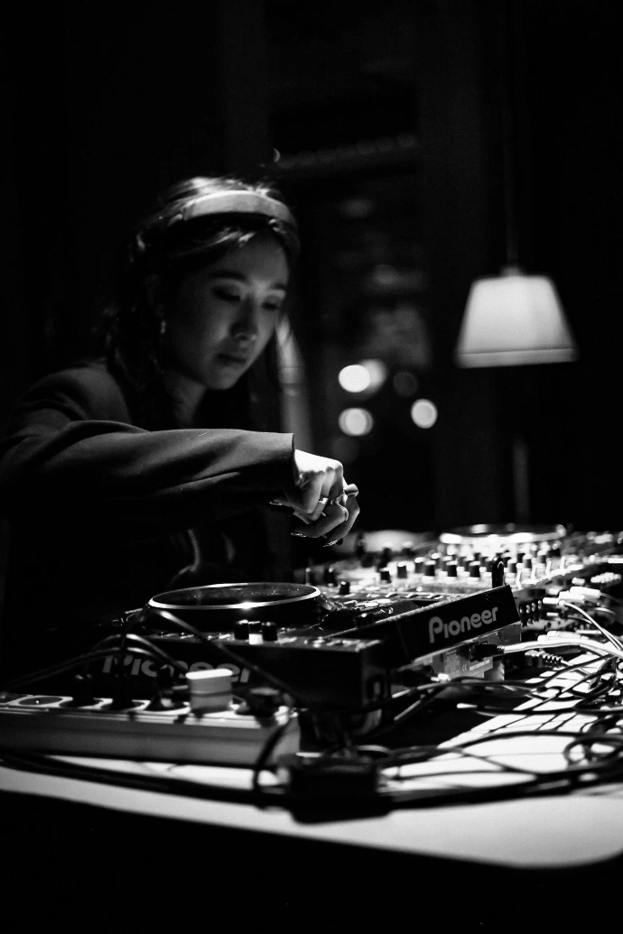 A woman djing at a soundboard in a dark room.